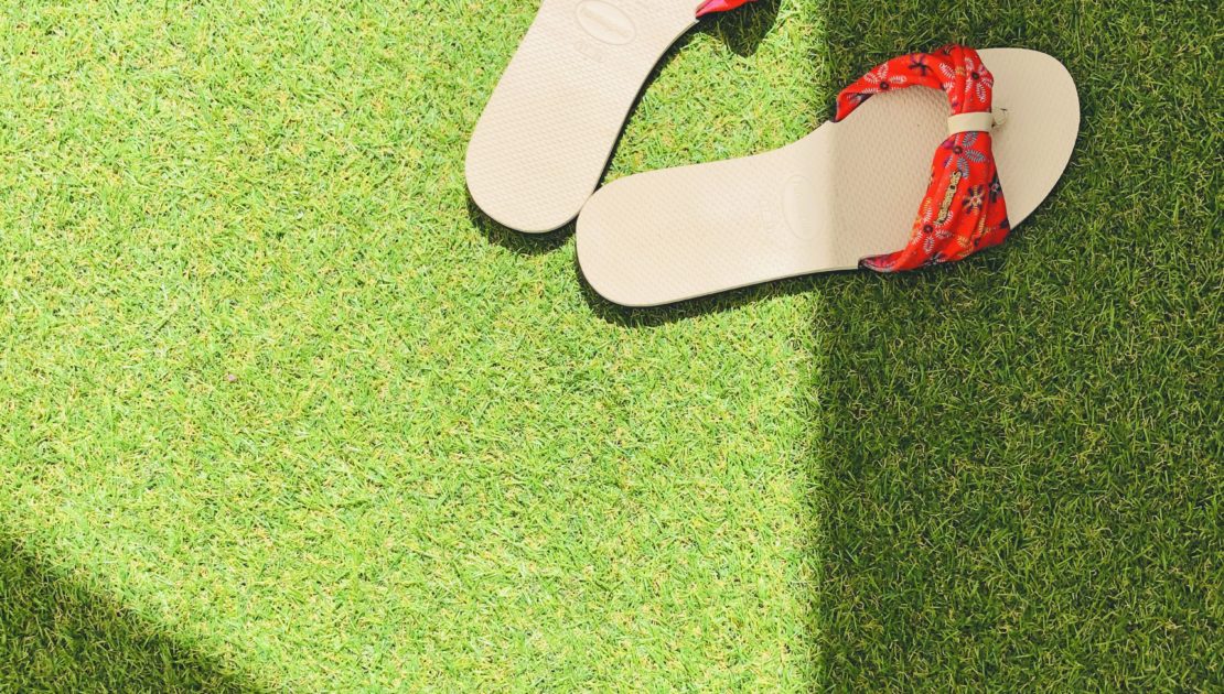 red flip flops on green artificial grass